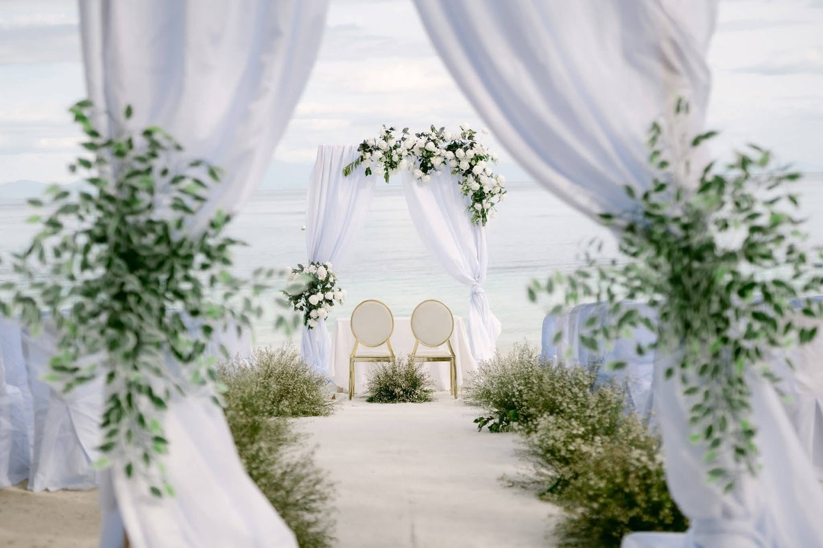 White floral wedding ceremony arch and aisle by the sea